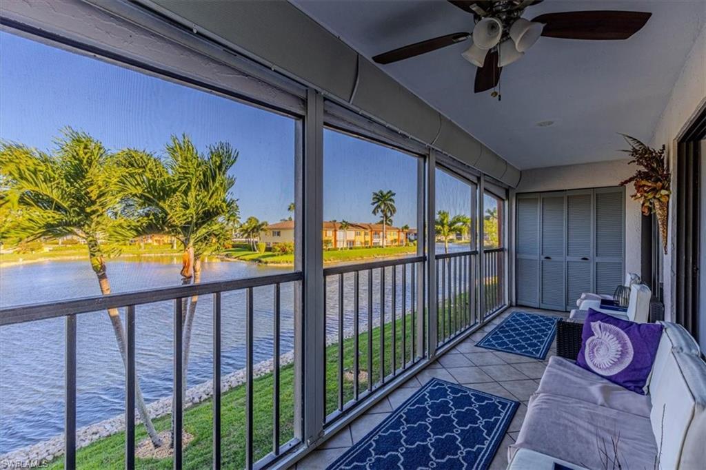 Sunroom with a water view, a ceiling fan, and tile patterned floors