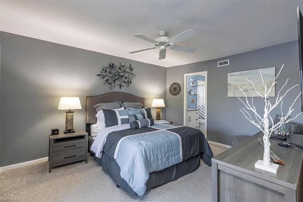 Carpeted bedroom with ceiling fan and ensuite bath