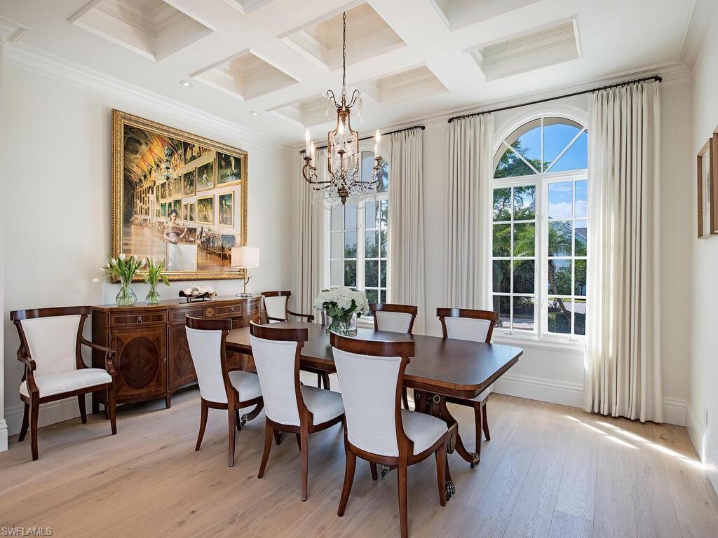 Dining room with a chandelier, crown molding, light wood-style flooring, coffered ceiling, and beam ceiling