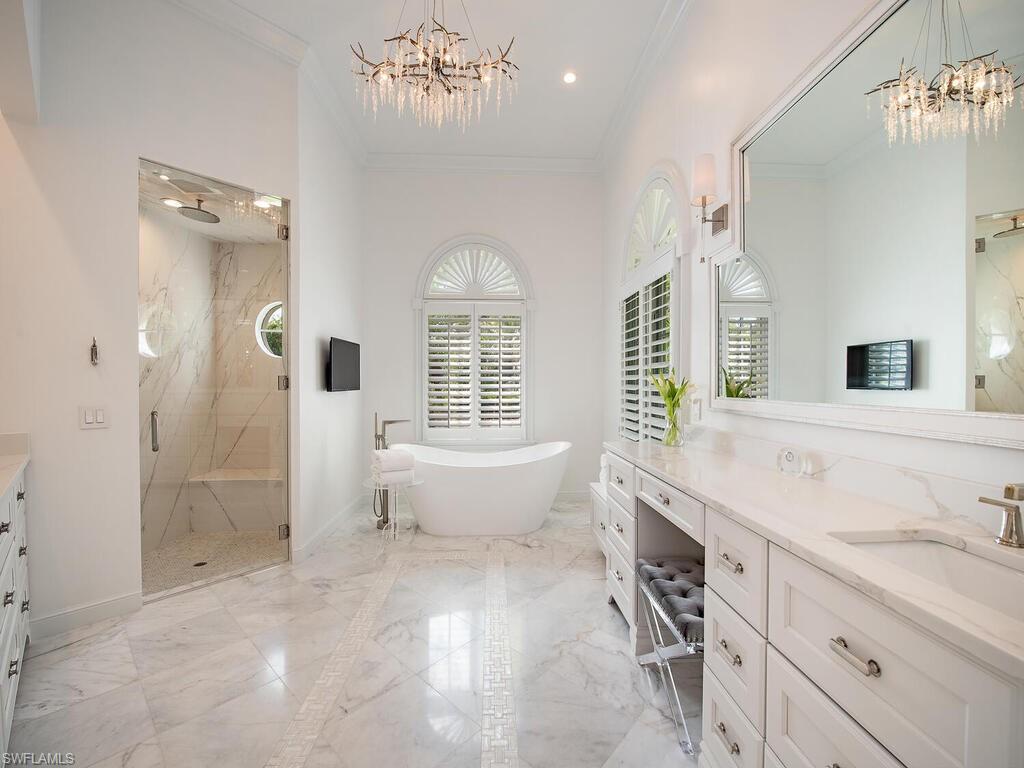Bathroom with vanity, a chandelier, a marble finish shower, light marble finish floors, and ornamental molding