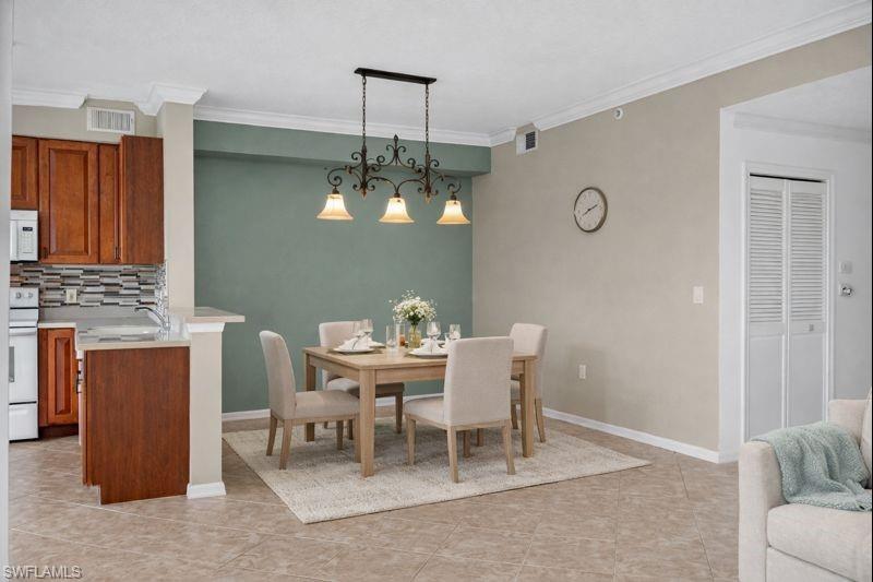 Dining room with ornamental molding and light tile patterned floors