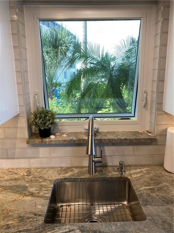 Kitchen view of a sink and dark stone counters