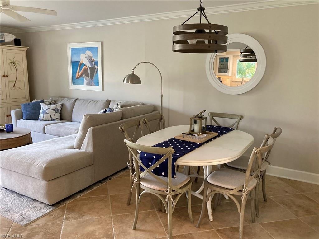Dining space with ornamental molding, light tile patterned flooring, and a ceiling fan