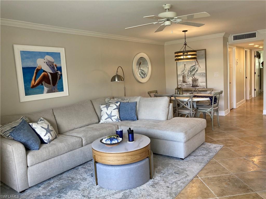 Living room featuring ornamental molding, a ceiling fan, and a chandelier