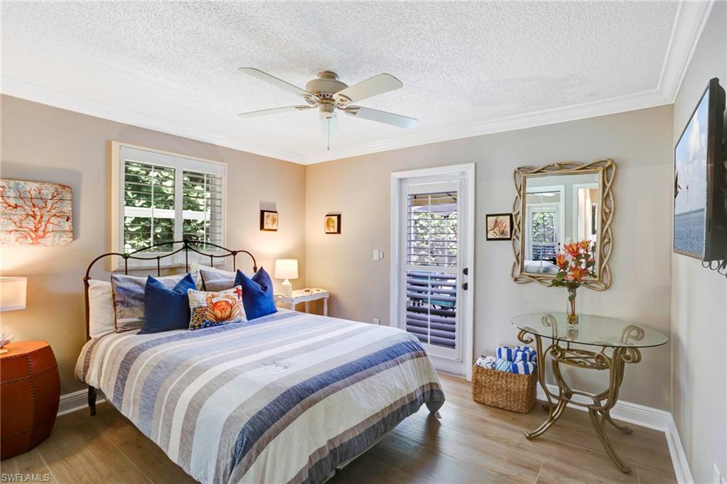 Bedroom featuring crown molding, hardwood / wood-style floors, access to exterior, and a textured ceiling
