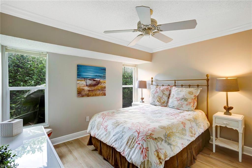 Bedroom featuring ceiling fan, ornamental molding, light hardwood / wood-style floors, and a textured ceiling
