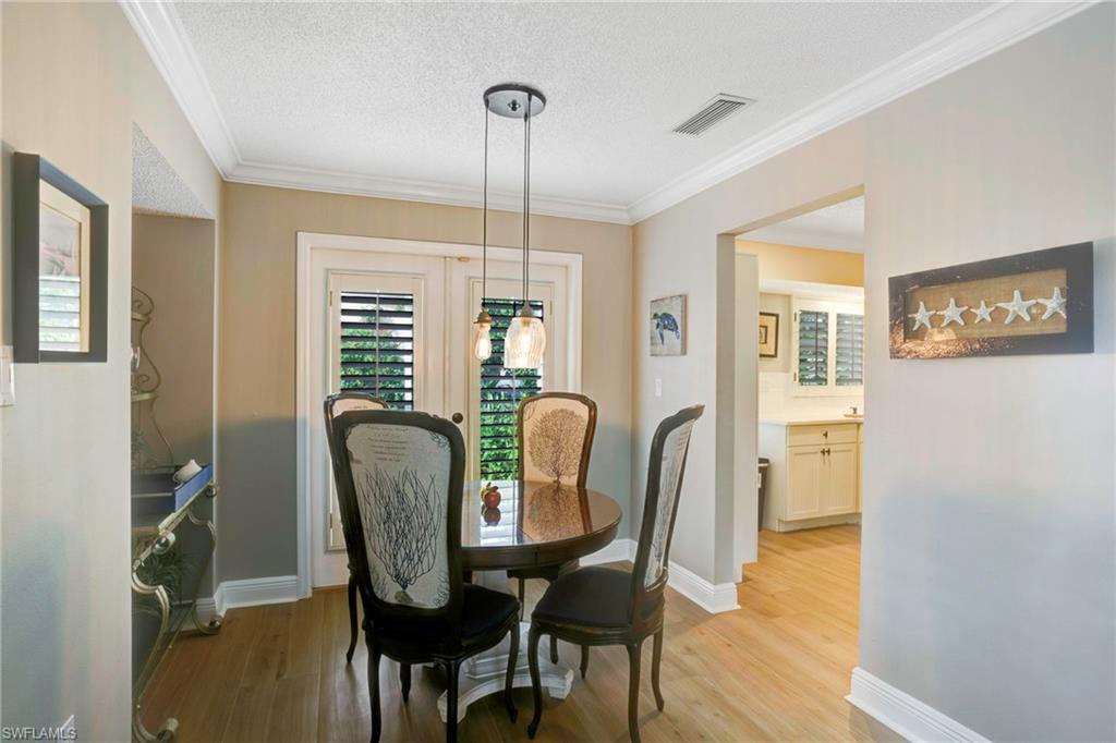 Dining space with crown molding, a textured ceiling, and light wood-type flooring