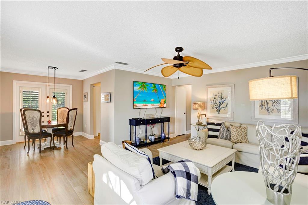 Living room with crown molding, light hardwood / wood-style flooring, a textured ceiling, and ceiling fan