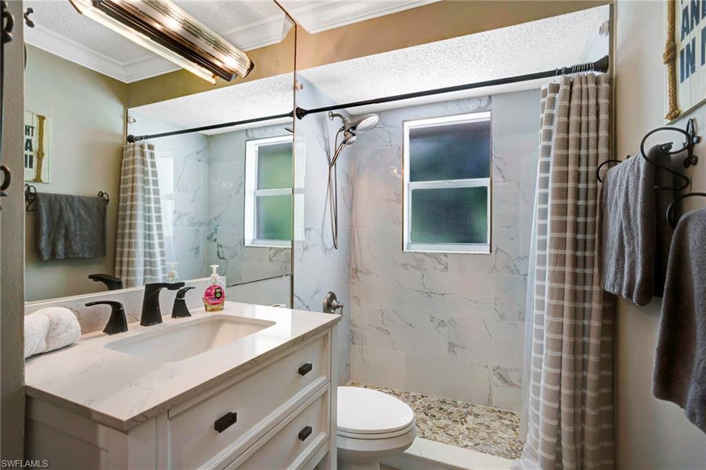 Bathroom featuring vanity, curtained shower, ornamental molding, and toilet