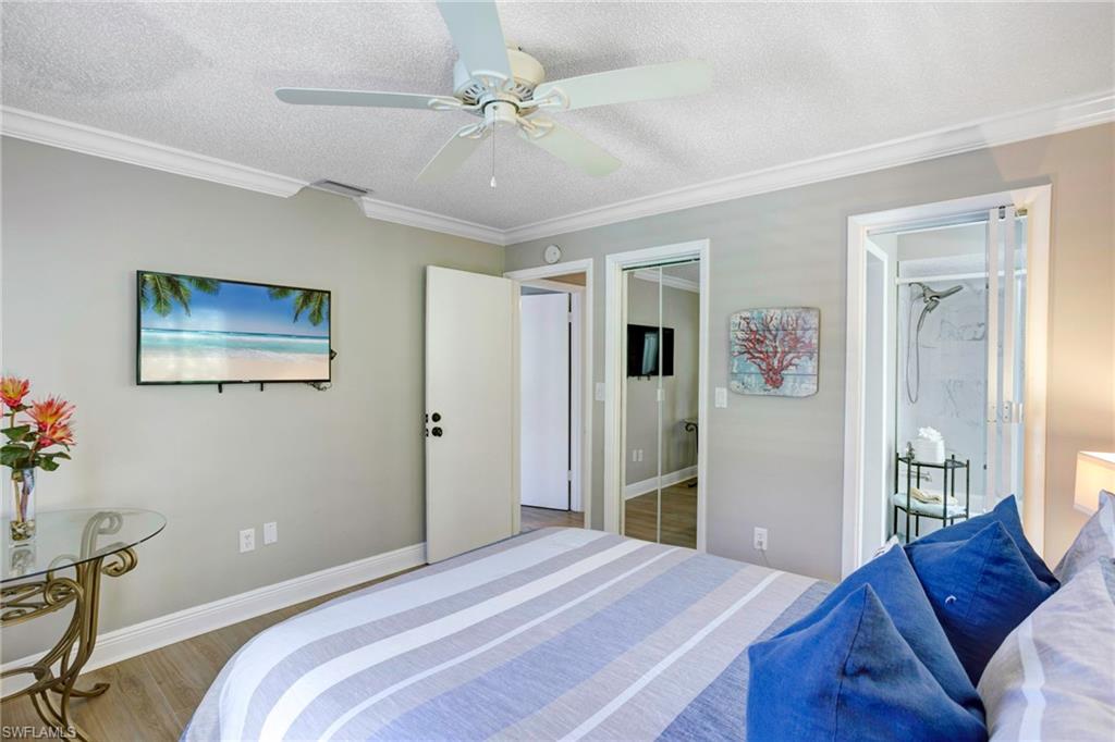 Bedroom with hardwood / wood-style flooring, ceiling fan, crown molding, and a textured ceiling