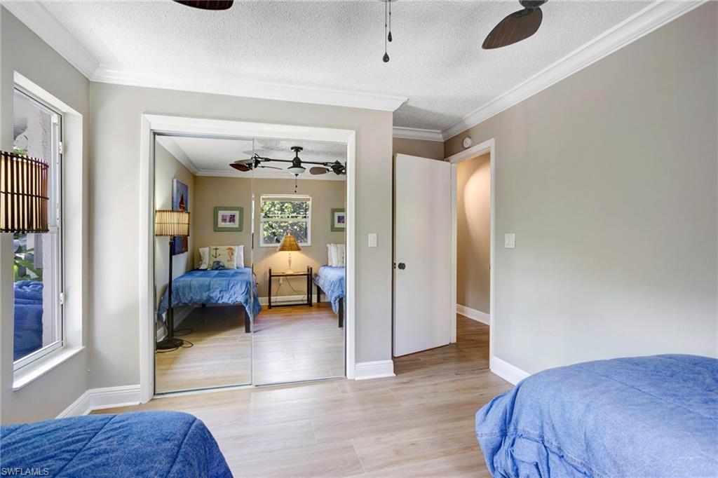 Bedroom featuring ceiling fan, ornamental molding, a textured ceiling, and light wood-type flooring