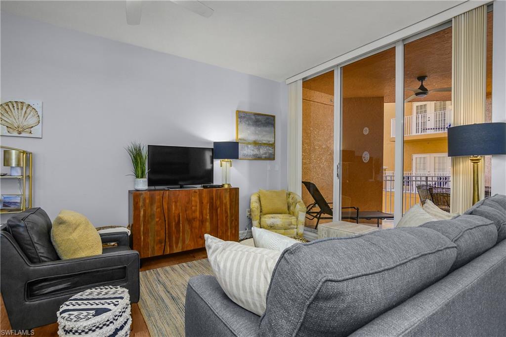 Living area featuring ceiling fan, expansive windows, and wood finished floors
