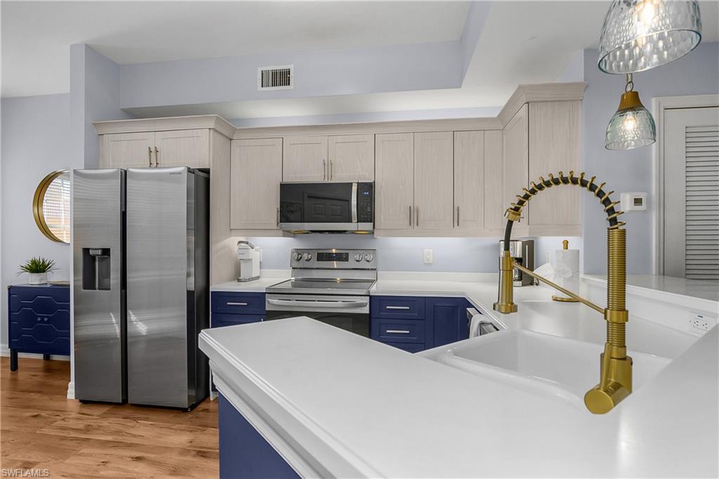 Kitchen featuring stainless steel appliances, light countertops, blue cabinets, and light wood-type flooring