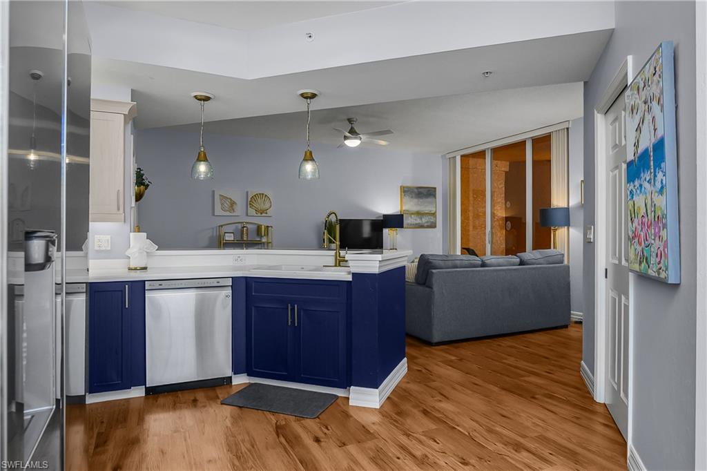 Kitchen featuring blue cabinetry, open floor plan, stainless steel appliances, hanging light fixtures, and a peninsula