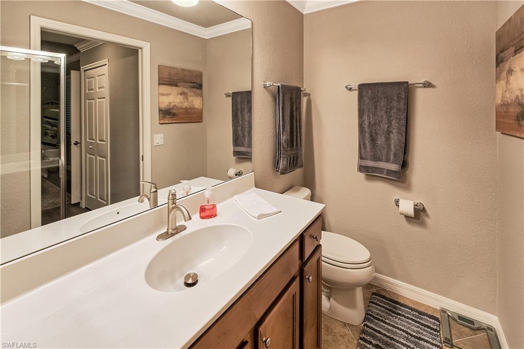 Bathroom with ornamental molding, vanity, toilet, and tile patterned floors