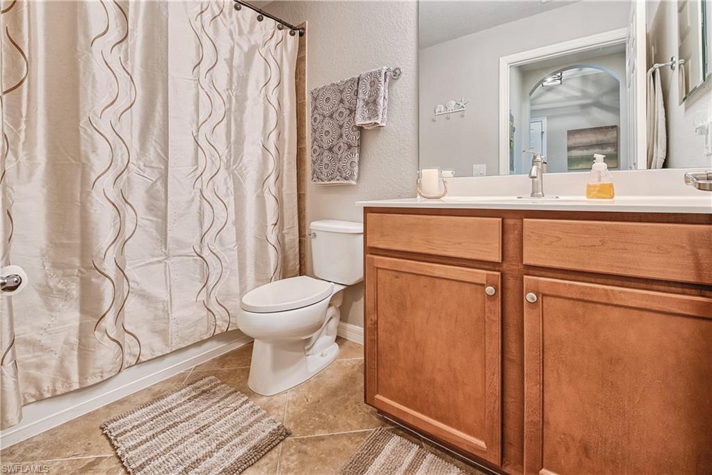 Bathroom with a shower with shower curtain, tile patterned flooring, vanity, and toilet