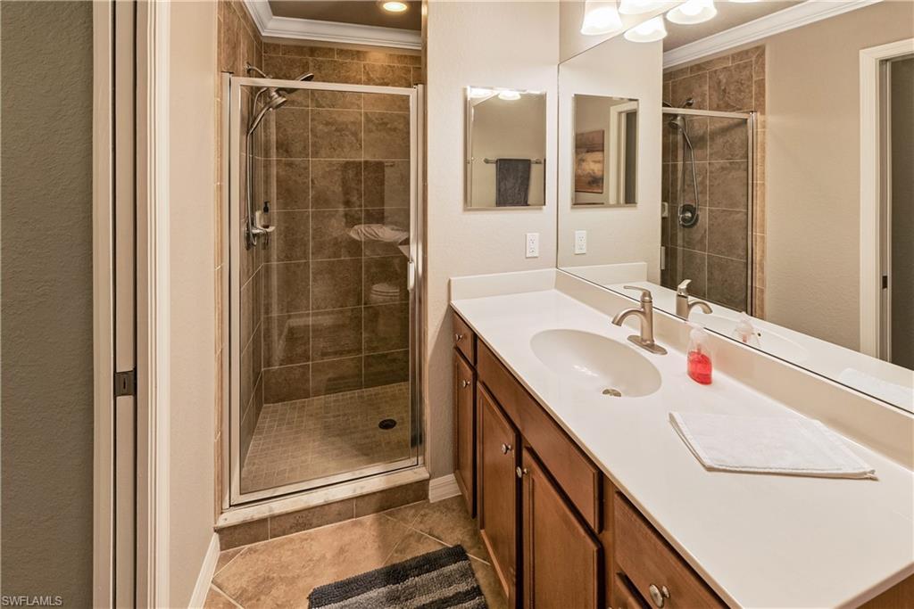 Bathroom with vanity, crown molding, an enclosed shower, and tile patterned floors