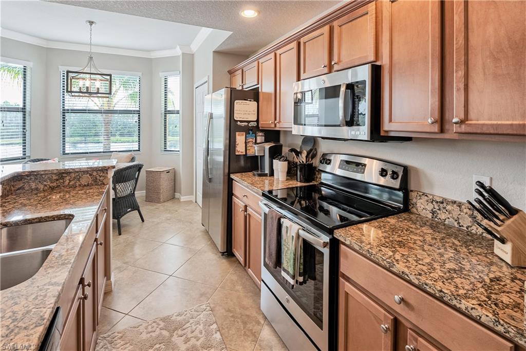 Kitchen with a textured ceiling, ornamental molding, stone countertops, and stainless steel appliances