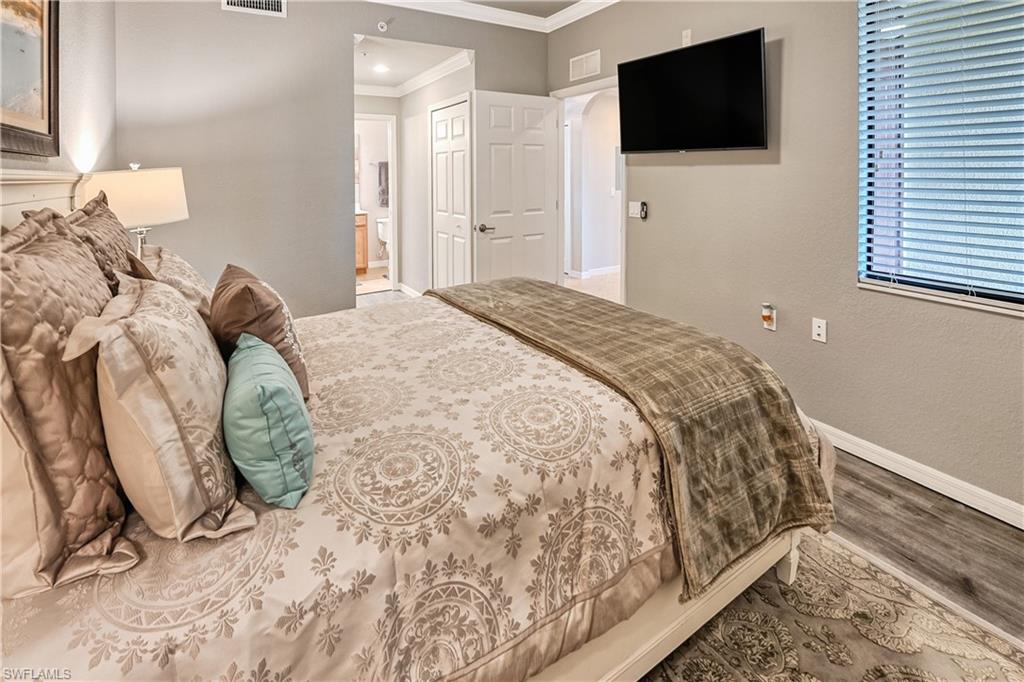 Bedroom featuring a closet, hardwood / wood-style floors, ensuite bathroom, and crown molding