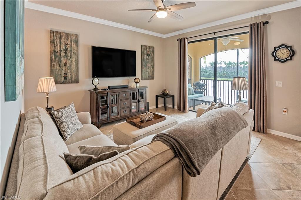 Living room featuring crown molding, light tile patterned floors, and ceiling fan