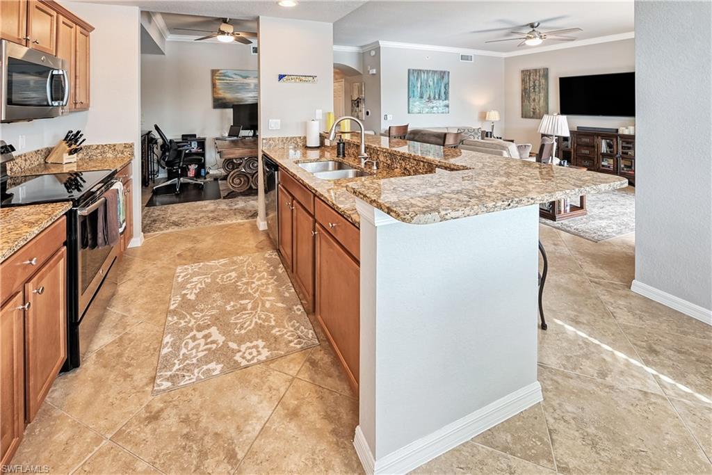 Kitchen with a breakfast bar, sink, stainless steel appliances, a center island with sink, and ornamental molding