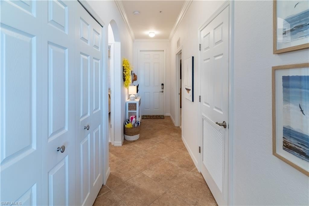 Hall featuring arched walkways, ornamental molding, and light tile patterned floors