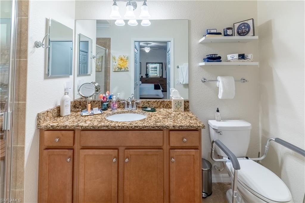 Ensuite bathroom featuring a shower stall, vanity, and a textured wall