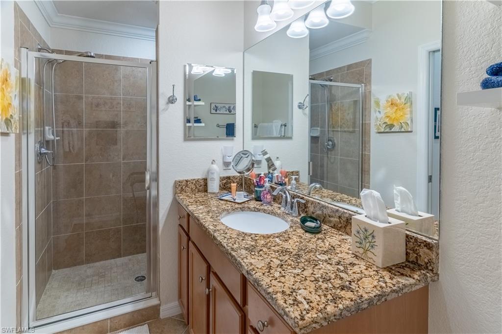 Bathroom featuring vanity, crown molding, a shower stall, and a textured wall