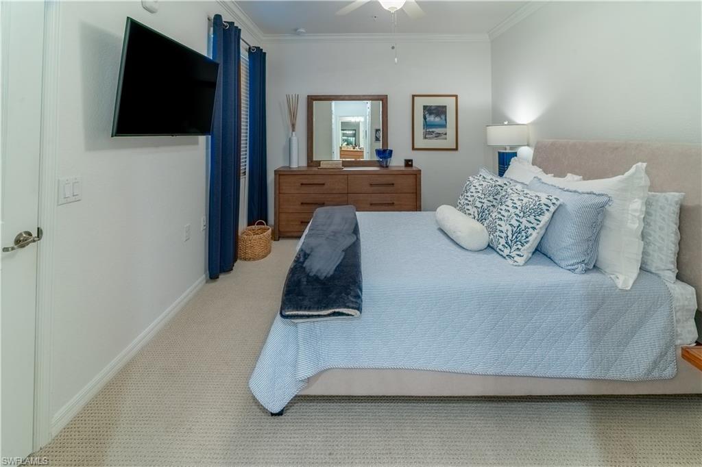 Carpeted bedroom featuring crown molding and ceiling fan