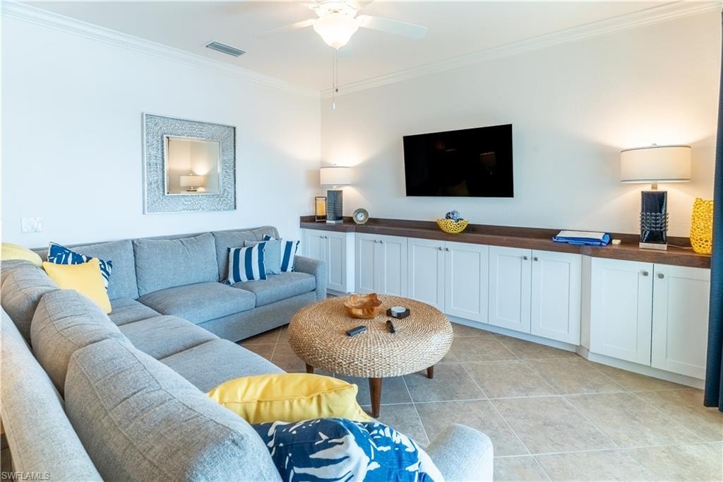 Living room with ornamental molding and light tile patterned flooring