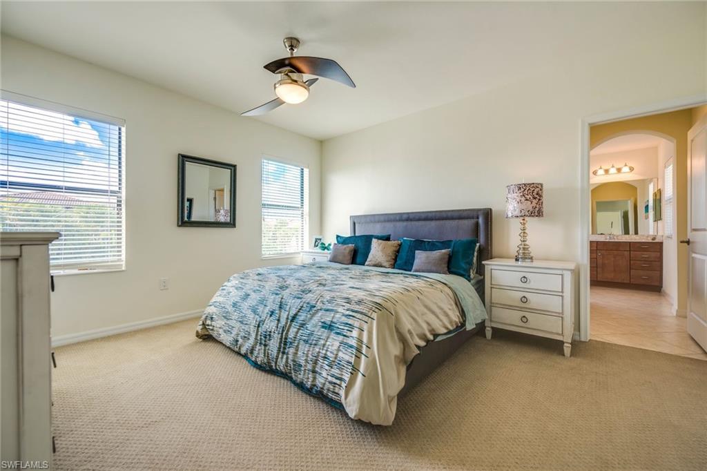 Bedroom with light carpet, a ceiling fan, connected bathroom, and arched walkways
