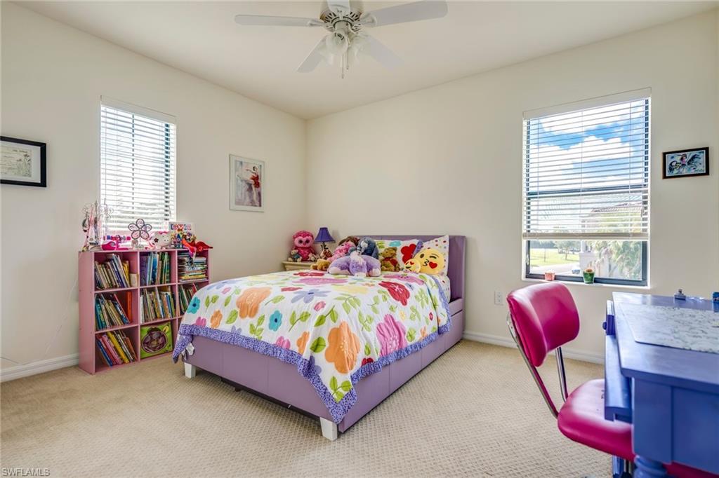 Carpeted bedroom featuring ceiling fan and baseboards