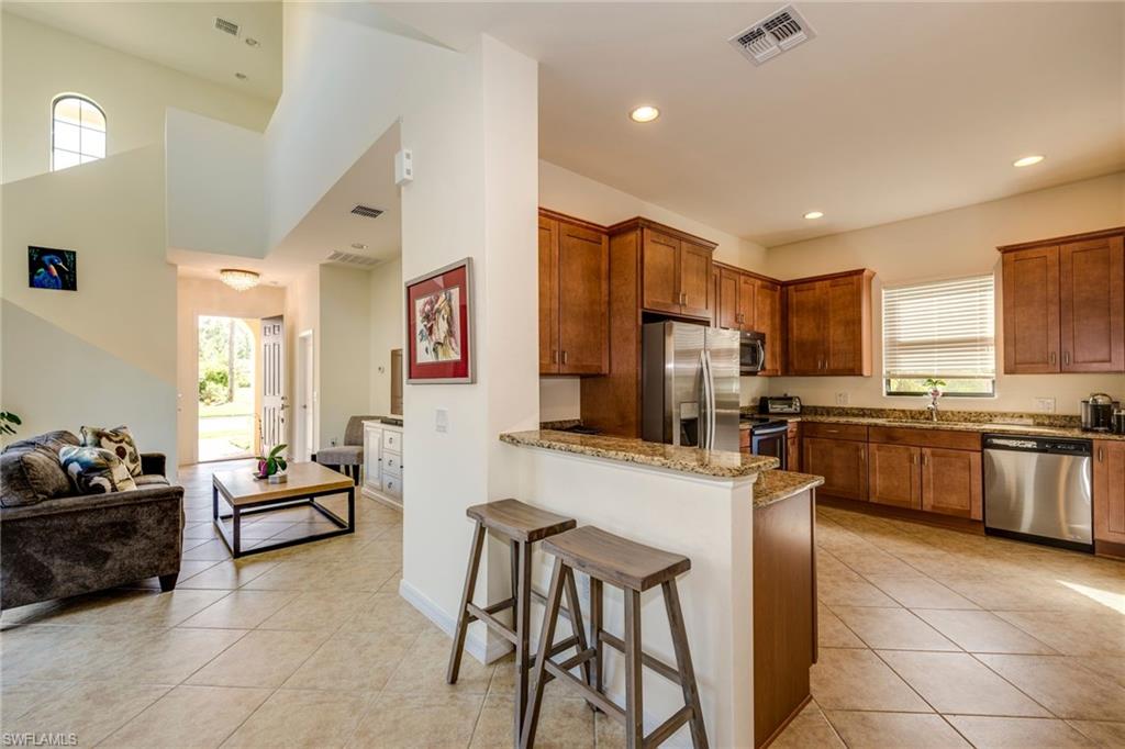Kitchen with a peninsula, healthy amount of natural light, light stone countertops, recessed lighting, and a towering ceiling