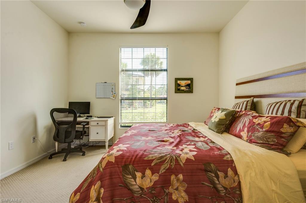 Carpeted bedroom with an office area and ceiling fan