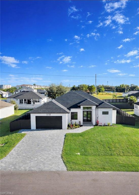 View of front of home featuring decorative driveway, an attached garage, stucco siding, roof with shingles, and a residential view