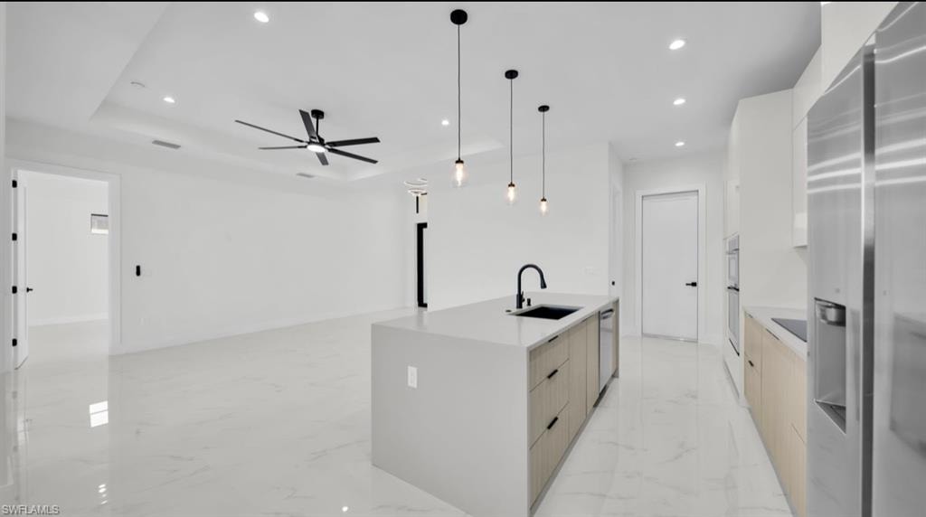 Kitchen with recessed lighting, stainless steel appliances, modern cabinets, pendant lighting, and light stone countertops