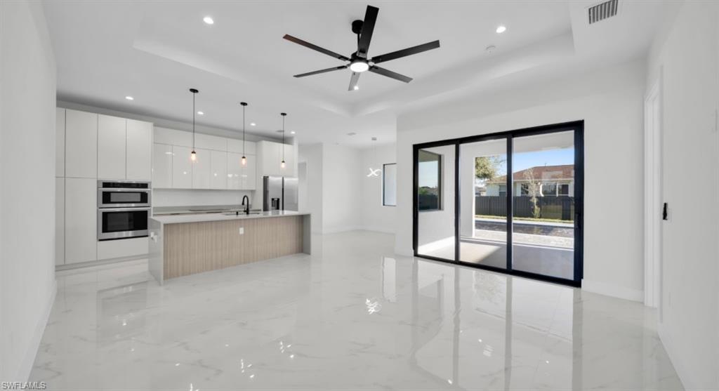 Kitchen featuring modern cabinets, white cabinetry, a tray ceiling, and recessed lighting