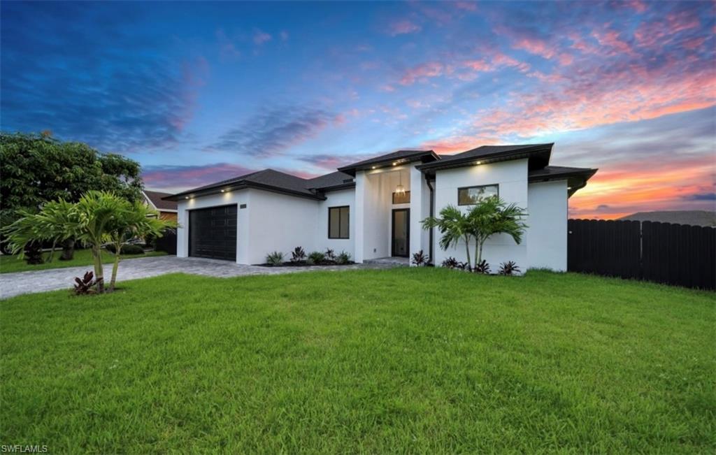 View of front of house featuring decorative driveway, an attached garage, and stucco siding