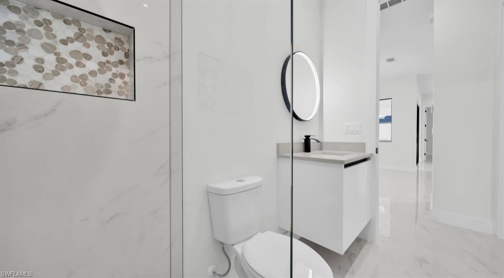 Full bath with light marble finish floors and vanity