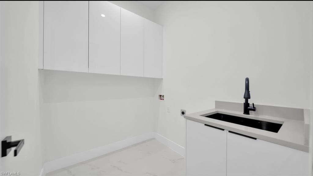 Laundry room featuring light marble finish flooring, cabinet space, and washer hookup