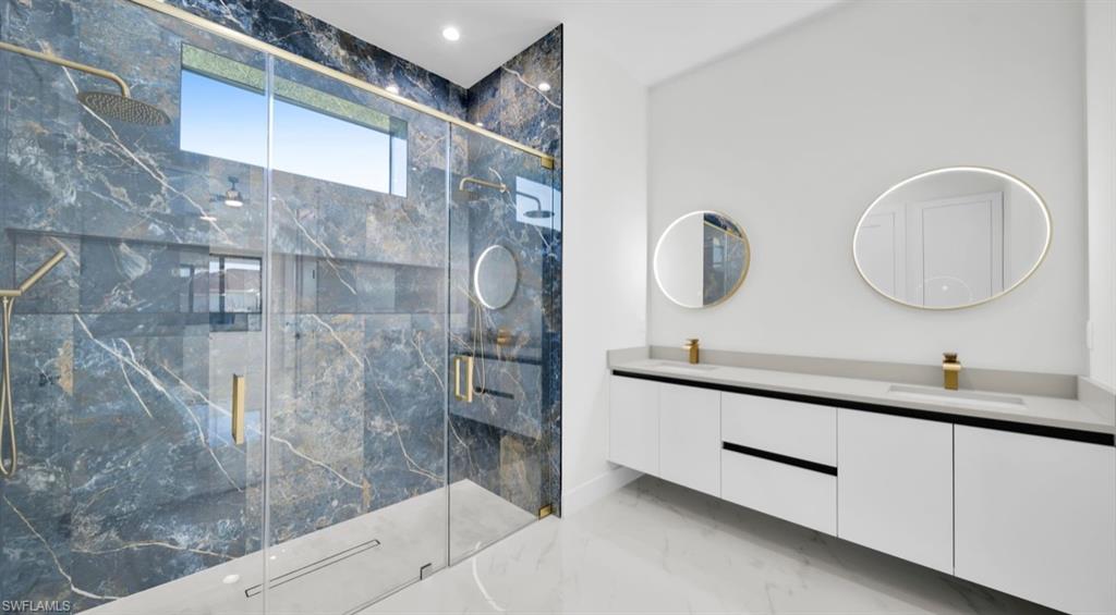 Bathroom with light marble finish floors, double vanity, a marble finish shower, and recessed lighting