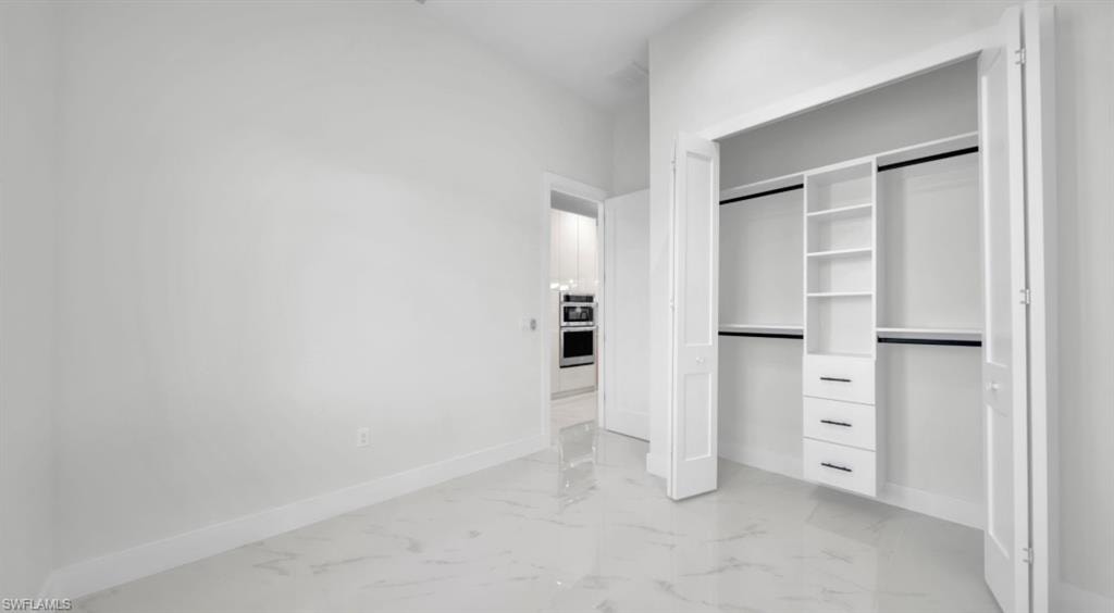 Unfurnished bedroom with a closet and light marble finish flooring