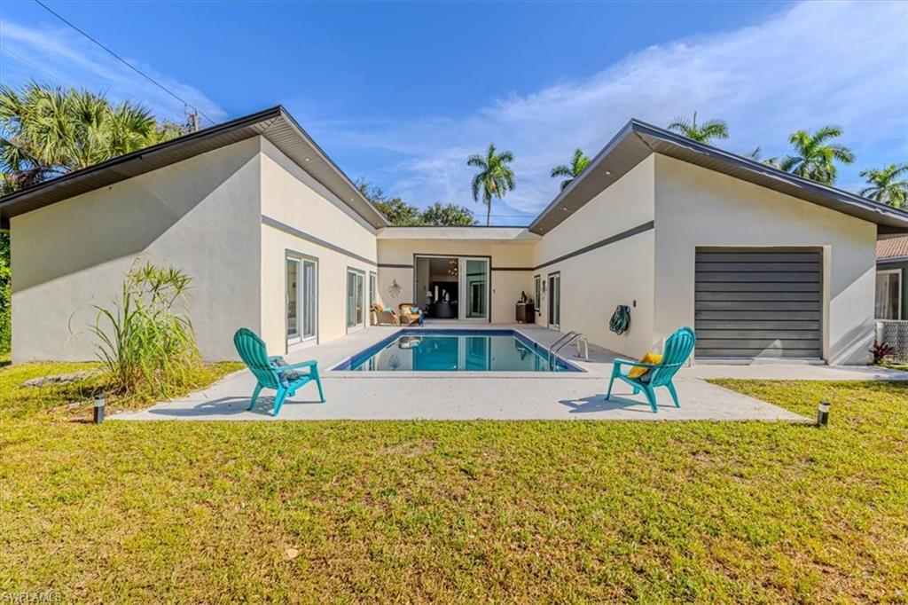Back of house featuring a lawn, a patio area, stucco siding, and an outdoor pool