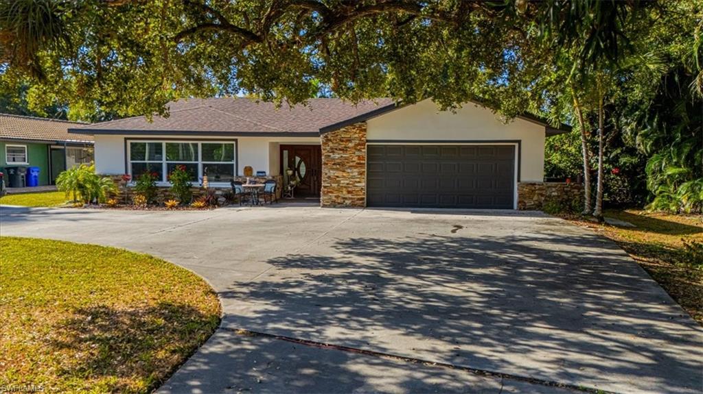 Ranch-style house with driveway, stone siding, stucco siding, and a garage