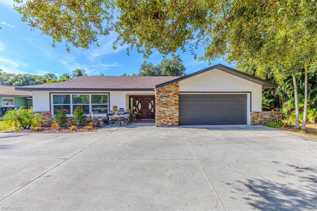 Ranch-style home featuring stucco siding, stone siding, driveway, and an attached garage