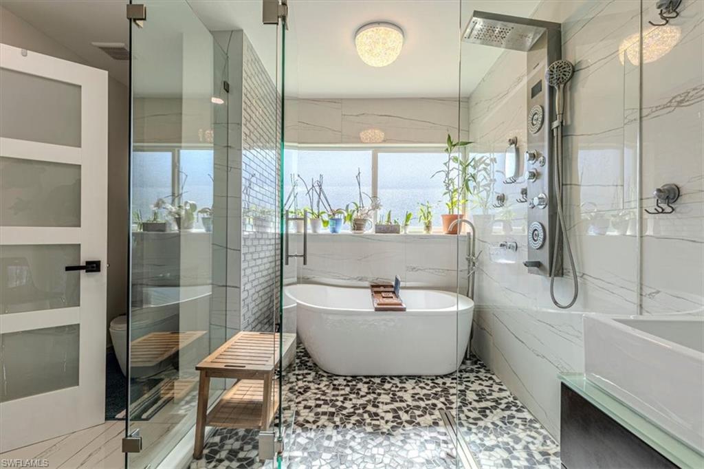 Full bath with a soaking tub, a marble finish shower, and tile walls