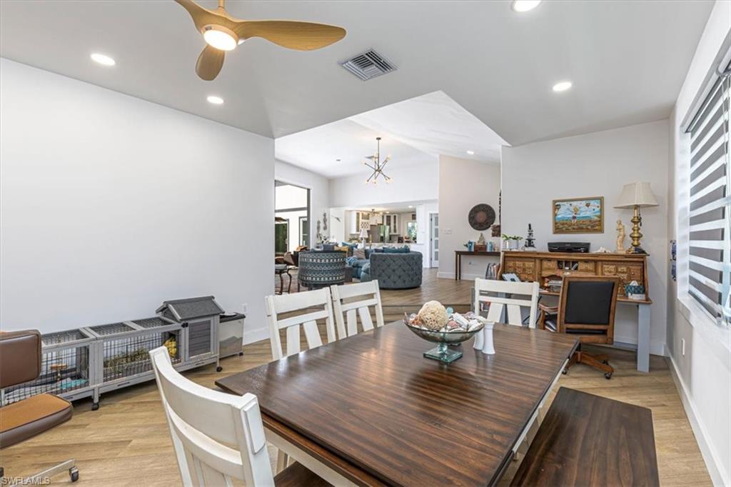 Dining area featuring recessed lighting, a ceiling fan, vaulted ceiling, light wood-style floors, and a chandelier