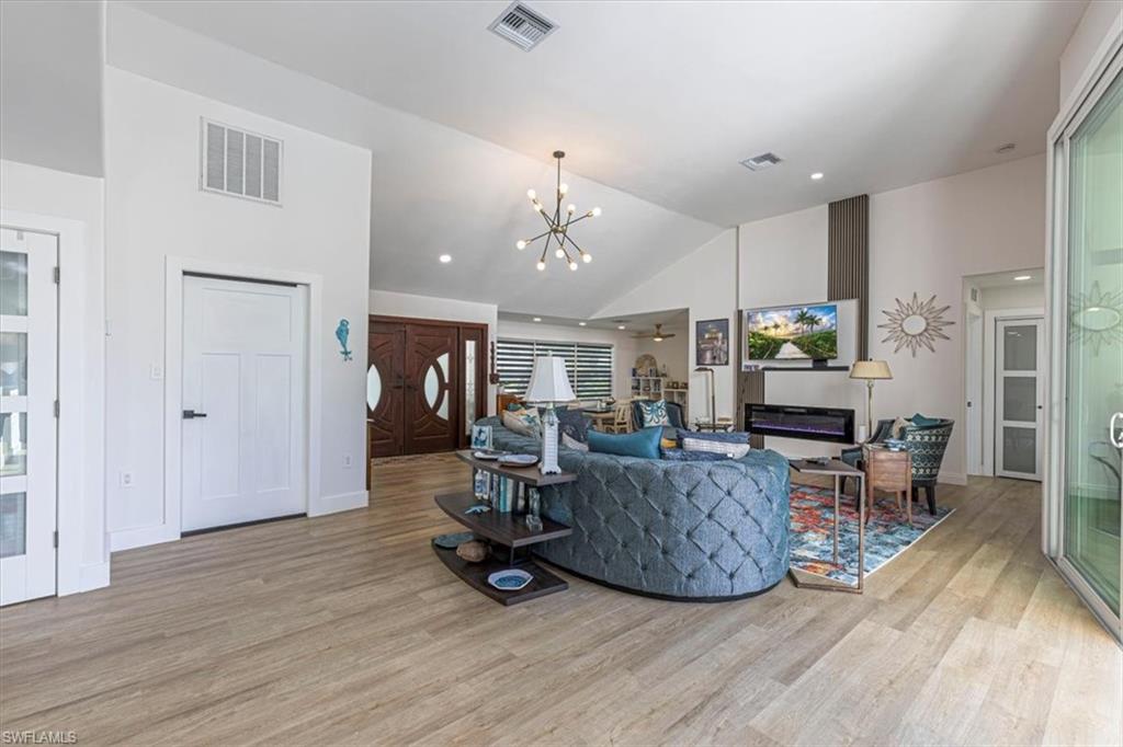 Living area with a chandelier, light wood finished floors, a ceiling fan, recessed lighting, and high vaulted ceiling