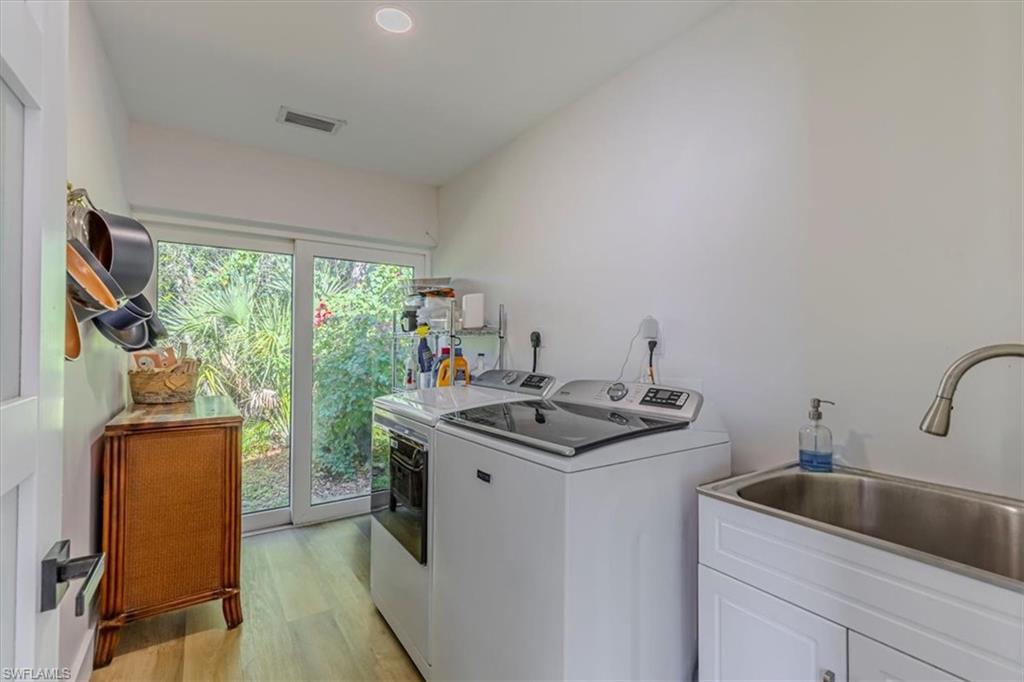 Washroom with light wood-type flooring, washer and dryer, and recessed lighting