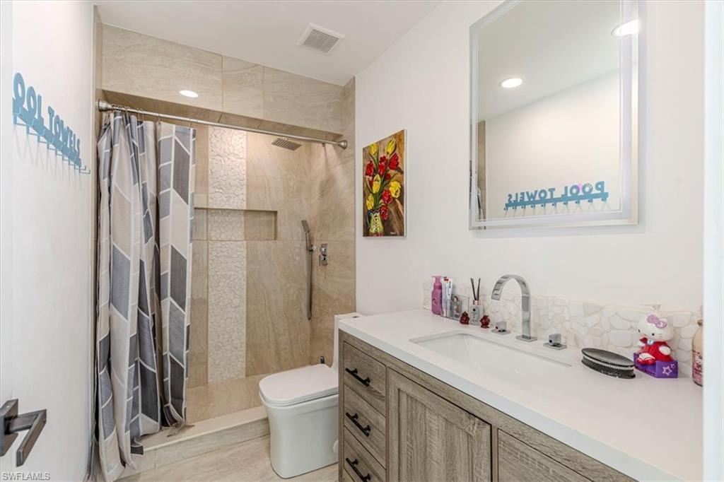 Bathroom featuring walk in shower, vanity, and recessed lighting